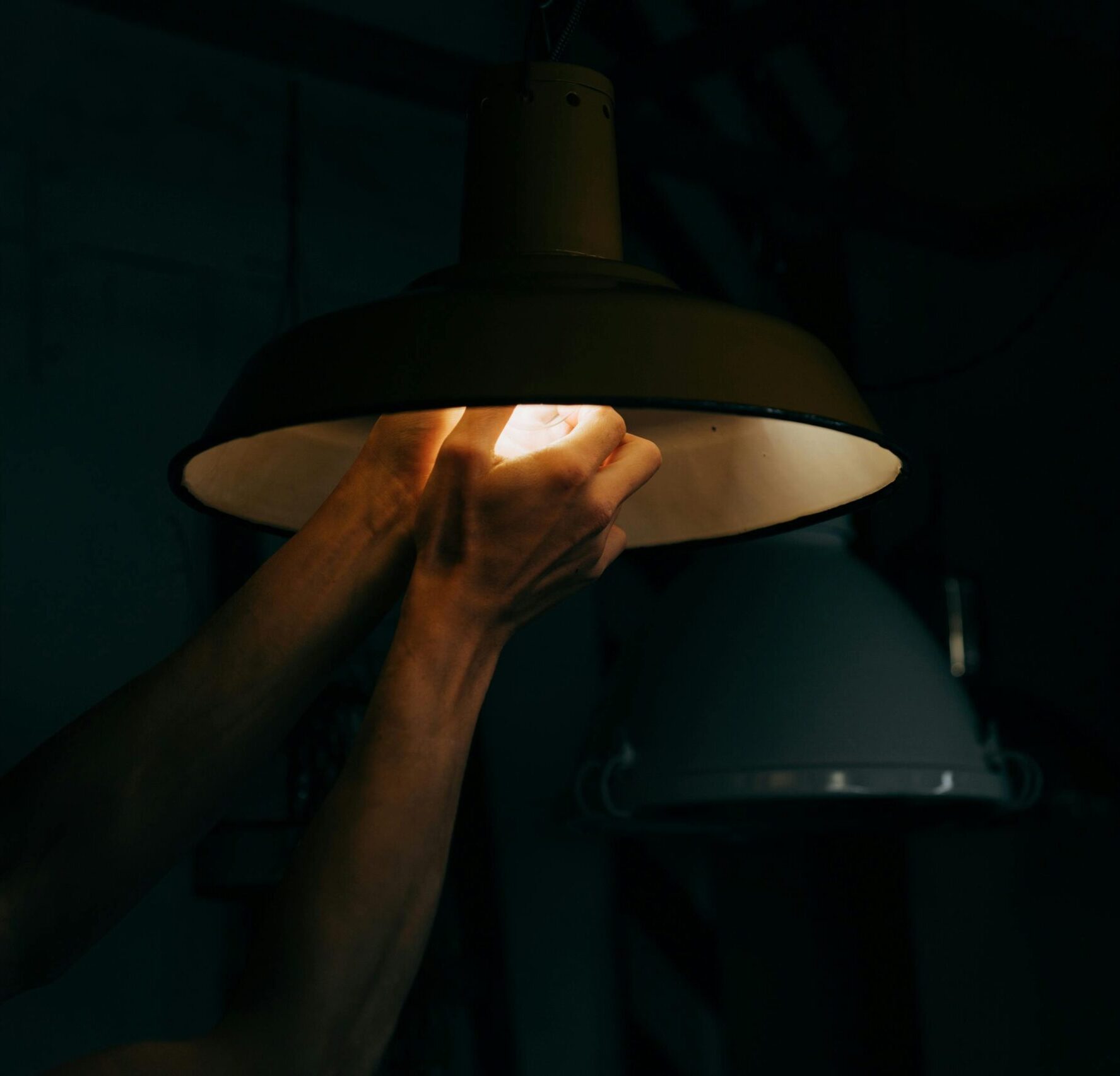 Hand screwing in lightbulb, dim lighting